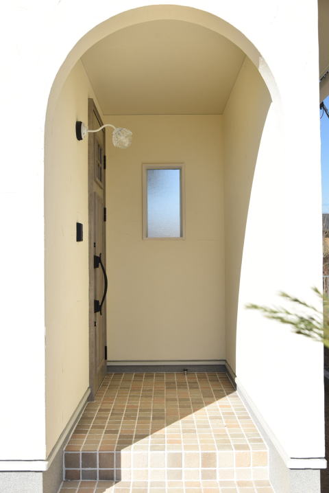 アンティーク調の2色MIXタイルとアーチ状の下がり壁の玄関ポーチ
